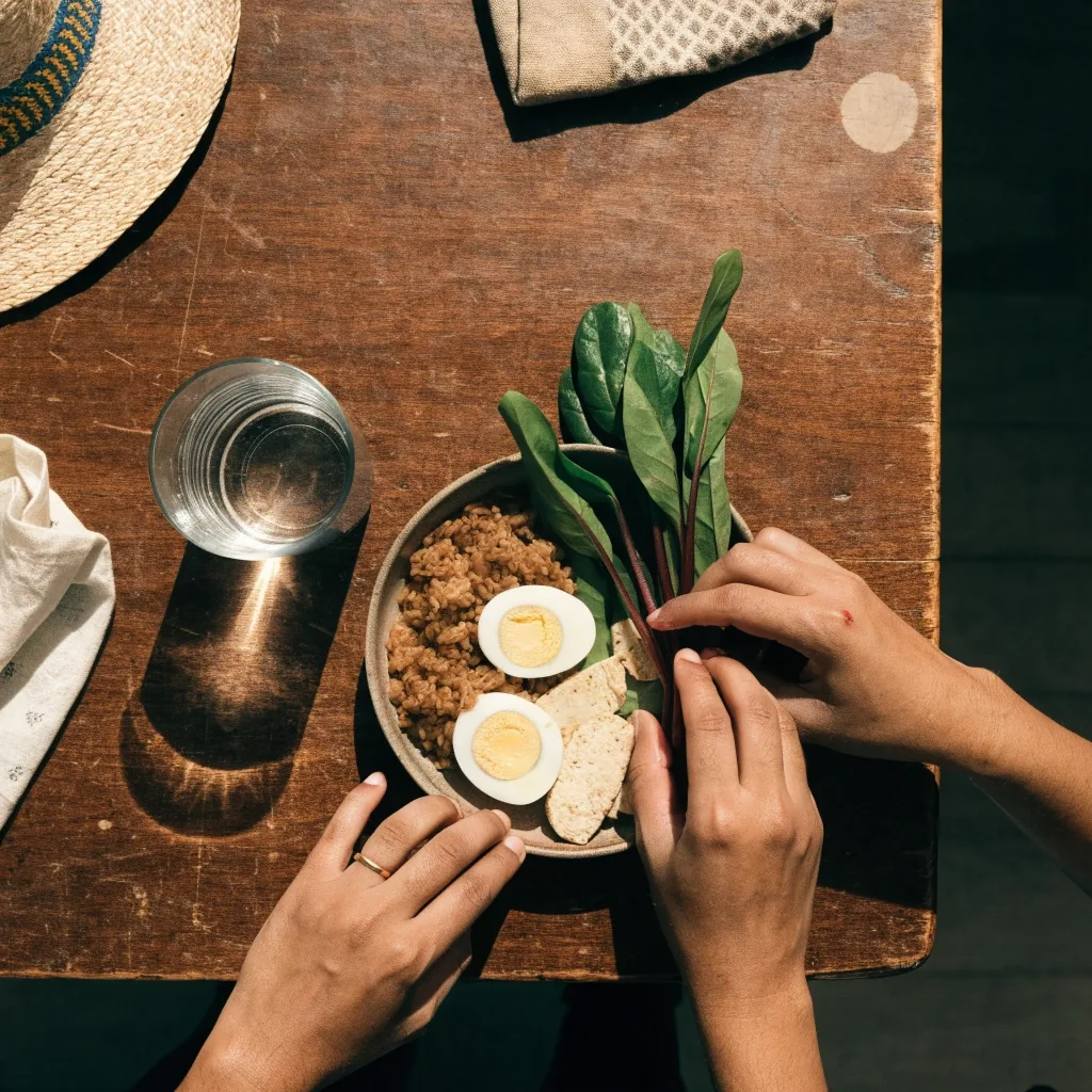 Overhead view of raw ingredients on a slate bench: legumes, seeds, dark greens, a fish fillet and a glass of iced water
